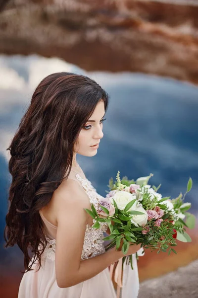 Stående kvinna med blå ögon och blombukett i händerna på naturen. Gorgeous hår och perfekt hud, vacker naturlig makeup. Flicka med en bukett rosor, mystiska dröm bild kvinna. — Stockfoto