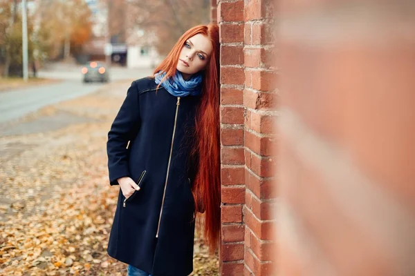 Frau mit langen roten Haaren geht im Herbst auf die Straße. geheimnisvoll verträumter Blick und das Bild des Mädchens. rothaarige Frau spaziert im Herbst durch die Stadt. kalter trüber Herbst in der Stadt. — Stockfoto