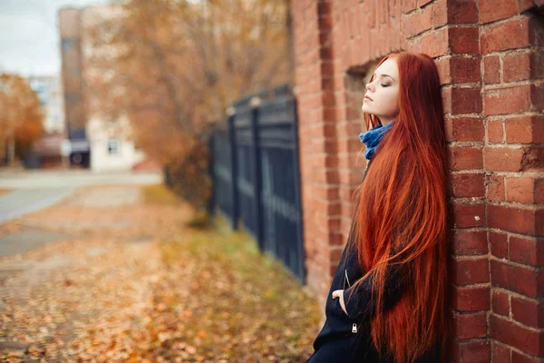 Žena s dlouhé červené vlasy chodí na podzim na ulici. Tajemný pohádkový vzhled a obraz dívky. Zrzka žena chůze na podzim město. Studená zataženo podzim ve městě. — Stock fotografie