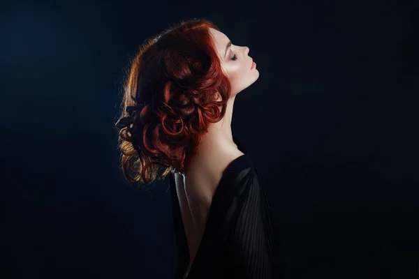 Hermosa mujer con el pelo rojo sobre un fondo negro. Retrato de — Foto de Stock