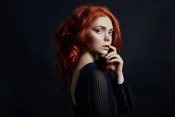 Mulher bonita com cabelo vermelho em um fundo preto. Retrato de — Fotografia de Stock