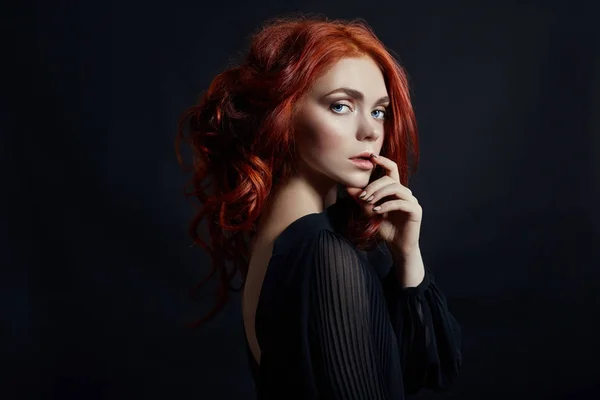 Hermosa mujer con el pelo rojo sobre un fondo negro. Retrato de — Foto de Stock