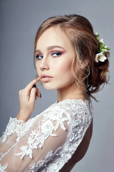 Joven novia en un lujoso vestido de novia blanco y hermoso cabello. Mujer antes de la ceremonia de la boda, una figura perfecta de la novia, hermoso maquillaje y peinado . — Foto de Stock