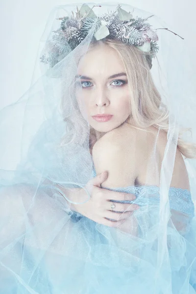 Charmiga fairy kvinna i en blå ethereal klänning och en krans på huvudet på vit bakgrund, mild mystiska blond tjej med perfekt hud och smink. Renlighet, kroppsvård och hud. — Stockfoto
