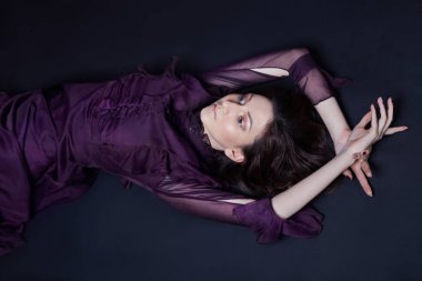 Kontrast moda Ermeni kadın portre mor bir elbise yerde yatan büyük mavi gözlü. Gece elbisesi içinde poz güzel güzel kız. Parlak makyaj, kadın.