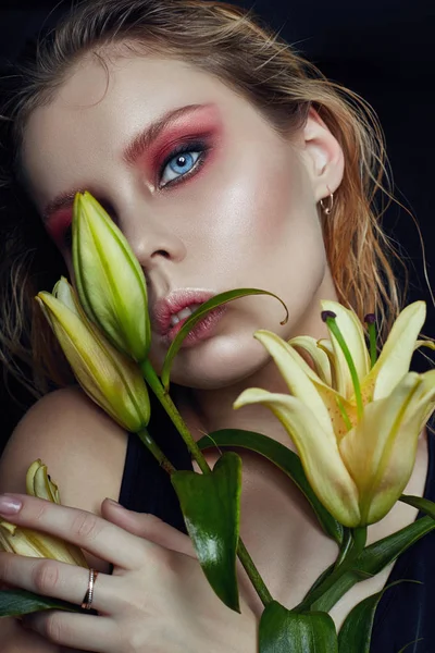 Closeup portrait of woman with flowers lilies in his hands, bright contrasting makeup on the girl's face. Wet hair and clean natural leather. — Stock Photo, Image