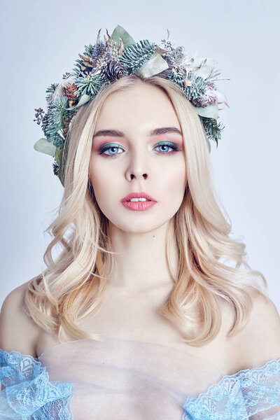 Portrait of a blonde woman with a wreath on her head and a blue 