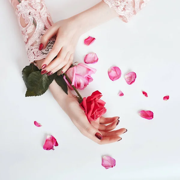 Mujer retrato de arte de moda en vestido de verano y flores en la mano con un maquillaje brillante contrastante. Chicas de fotos de belleza creativa sentadas a la mesa sobre un fondo rosa contrastante con sombras de colores . —  Fotos de Stock