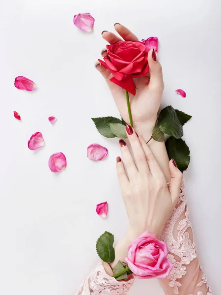 Ritratto d'arte di moda donna in abito estivo e fiori in mano con un trucco brillante a contrasto. Creativa bellezza foto ragazze sedute a tavola su uno sfondo rosa a contrasto con ombre colorate . — Foto Stock