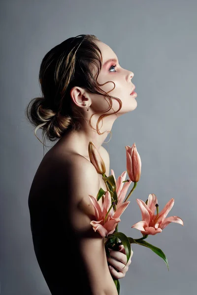 Art beauty girl face closeup with lilies in hands on grey backgr — Stock Photo, Image