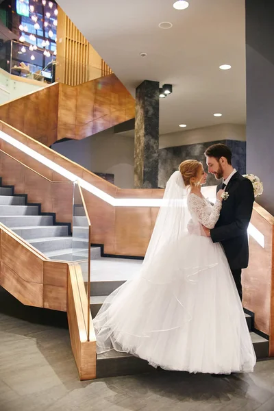 Bride and groom hugging and kissing while standing on the stairs