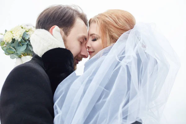 Bride and groom hugging and kissing while standing on the street