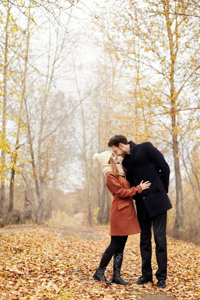 Loving couple walks in the autumn Park, hugs and kisses. Woman i