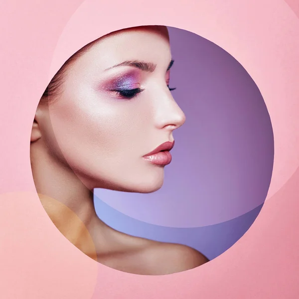 Skönhet smink kosmetika natur mode kvinna i ett runt hål cirklar i rosa papper, kopiera utrymme reklam. Professionell makeup perfekt hud och glänsande läppstift. Annonsering av banret, bokomslag. — Stockfoto