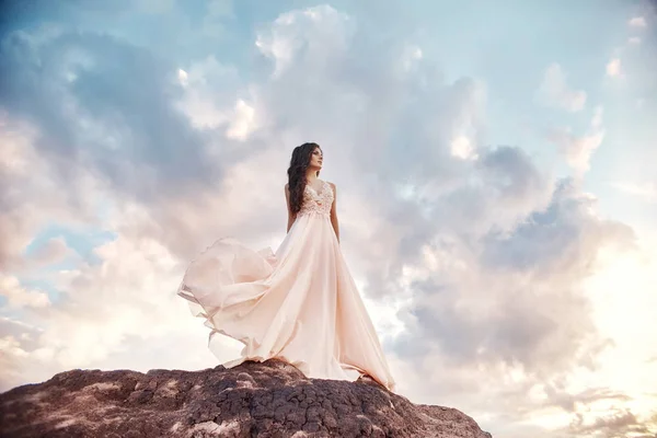 Piękna dziewczyna w jasny lato sukienka beż spacery w górach. Lekka sukienka powiewa w wiatr, niebieski niebo latem. Fantastyczny wiosnę krajobraz, brunetka dosiada krater wulkanu. — Zdjęcie stockowe
