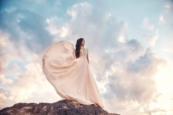 Prachtige vrouw brunette in de bergen bij zonsondergang en blauwe hemel — Stockfoto