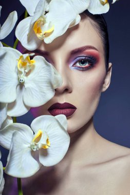 Onun elinde beyaz orkide bir dalı ile güzel çıplak kadın,
