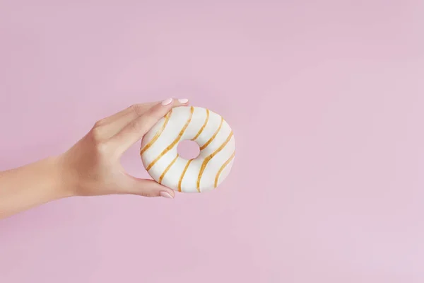 Menina segurando um donut na mão em um fundo rosa. Doces um — Fotografia de Stock