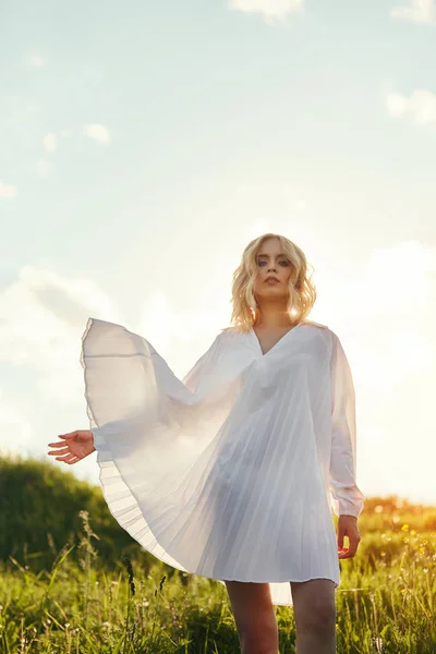 Ragazza con un lungo vestito bianco che balla sul campo. Donna bionda in — Foto Stock