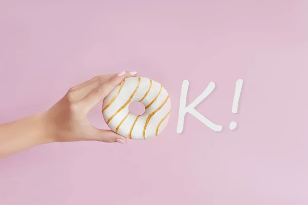 Está bem. Menina segurando um donut na mão em um fundo rosa. Doce. — Fotografia de Stock