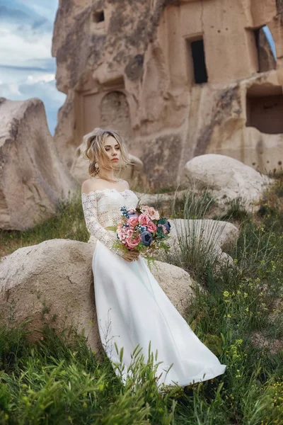Girl in a long wedding dress with a bouquet of flowers in her ha — Stock Photo, Image