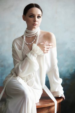 İnce, güzel, esmer kız. Kanepede oturuyor.