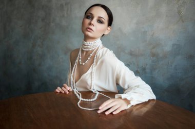 İnce, güzel, esmer kız. Kanepede oturuyor.