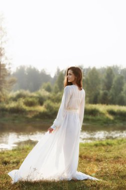 Sabahları uzun beyaz elbiseli güzel, ince bir kadın yürüyor.