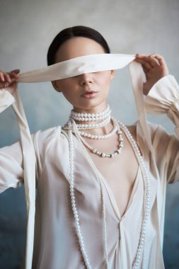 İnce, güzel, esmer kız. Kanepede oturuyor.