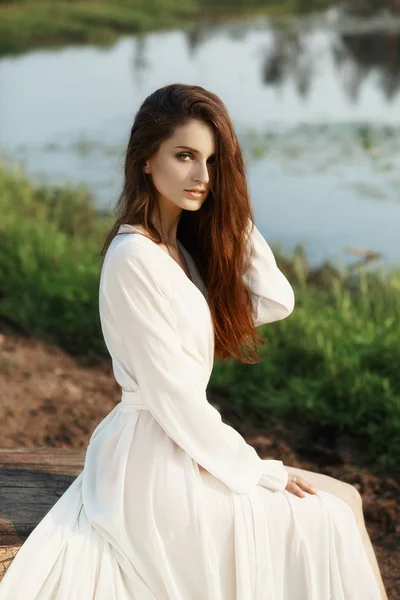 Mooie slanke vrouw in een lange witte jurk wandelingen in de ochtend — Stockfoto