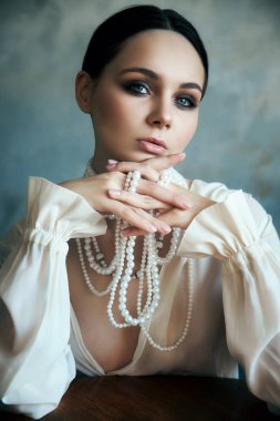 Beyaz boho elbiseli, beyaz inci boncuklu bir kız.