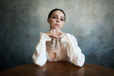 Beyaz boho elbiseli, beyaz inci boncuklu bir kız.