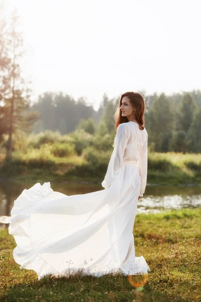 Sabahları uzun beyaz elbiseli güzel, ince bir kadın yürüyor. — Stok fotoğraf