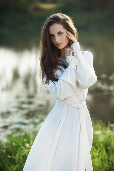 Gyönyörű karcsú nő hosszú fehér ruhában sétál reggelente. — Stock Fotó