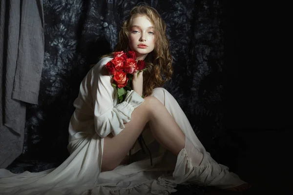 Красива весняна дівчина сидить на підлозі з трояндовими квітами — стокове фото