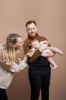 Bir erkek ve bir kadın bir bebeği kollarında tutuyorlar. Evli birinin portresi.