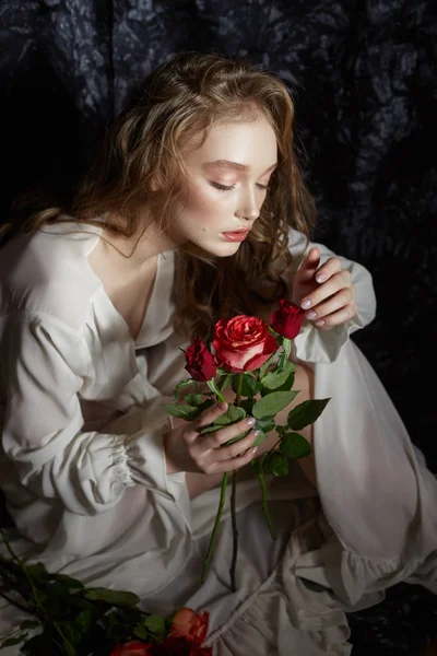 Όμορφη κοπέλα της άνοιξης κάθεται στο πάτωμα με τριαντάφυλλο λουλούδια — Φωτογραφία Αρχείου