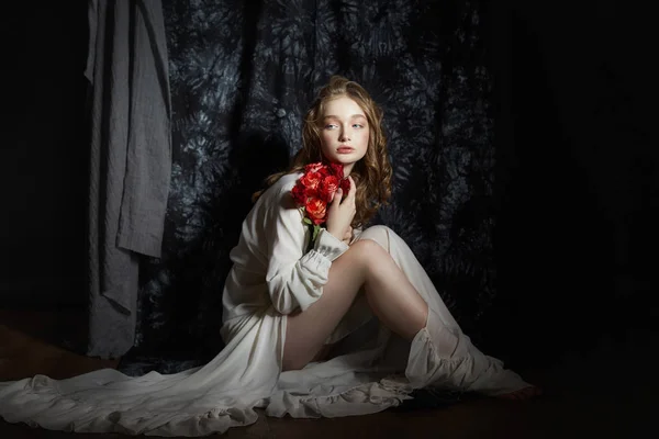 Krásná jarní dívka sedí na podlaze s růžovými květy — Stock fotografie