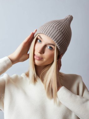 Bahar elbiseli bir kadın, Snood atkısı, şapka ve eldiven. Kız mavi gözlü sarışındır. Soğuk bahar havası için sıcak kıyafetler.