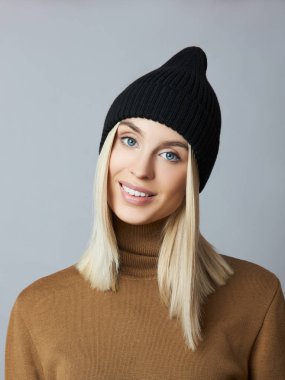 Bahar elbiseli bir kadın, Snood atkısı, şapka ve eldiven. Kız mavi gözlü sarışındır. Soğuk bahar havası için sıcak kıyafetler.
