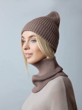Bahar elbiseli bir kadın, Snood atkısı, şapka ve eldiven. Kız mavi gözlü sarışındır. Soğuk bahar havası için sıcak kıyafetler.