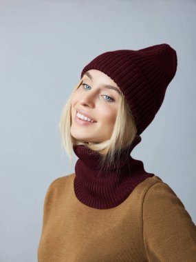 Bahar elbiseli bir kadın, Snood atkısı, şapka ve eldiven. Kız mavi gözlü sarışındır. Soğuk bahar havası için sıcak kıyafetler.