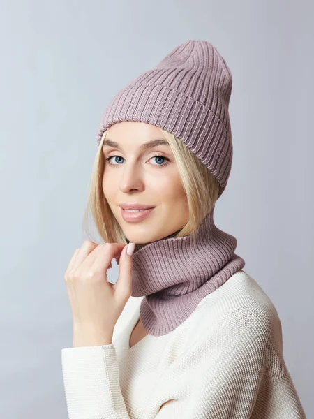 Bahar elbiseli bir kadın, Snood atkısı, şapka ve eldiven. Kız mavi gözlü sarışındır. Soğuk bahar havası için sıcak kıyafetler.