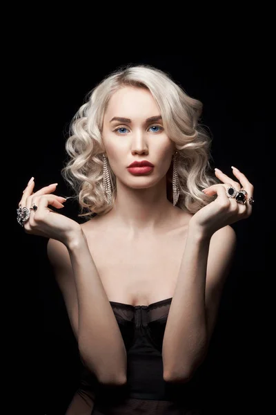 Beauty fashion woman with jewelry on her hands, wavy hair. Portrait of a blonde girl with rings on her fingers, beautiful makeup on her face, perfect hair styling