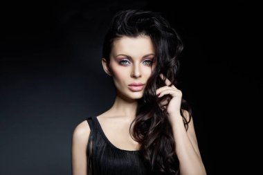 Şık, dalgalı saçlı, dolgun dudaklı esmer bir kadının portresi. Doğal kozmetik ürünleri ve güzel, parlak makyajlı bir kız.