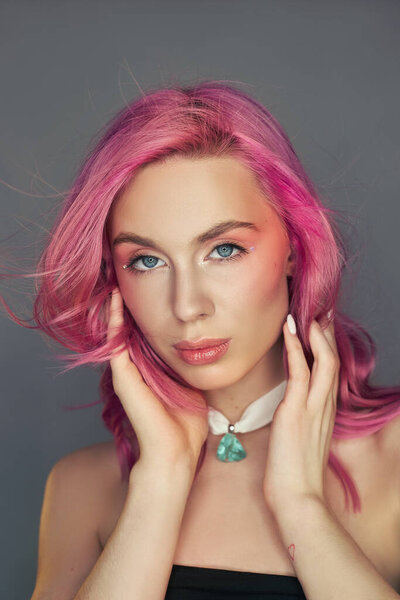 Beauty portrait woman with pink hair, creative vivid coloring. Bright colored highlights and shadows color on the face, a girl with jewelry. Dyed hair in the wind