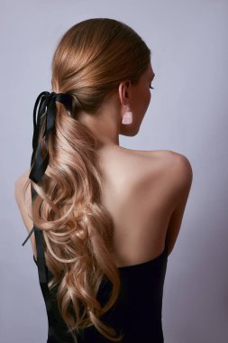 Uzun saçlı, kulaklarında küpeler ve ellerinde pahalı mücevherler olan bir kadının güzel portresi.