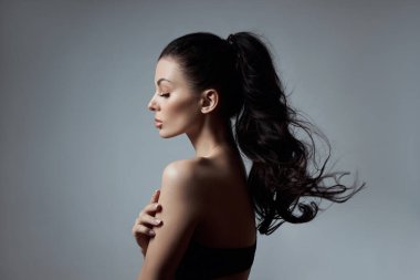 Uzun saçlı, kıvırcık saçlı, iç çamaşırlı esmer bir kızın seksi moda kadını. Saç bakımı için doğal kozmetik ürünleri, güçlü kökler.