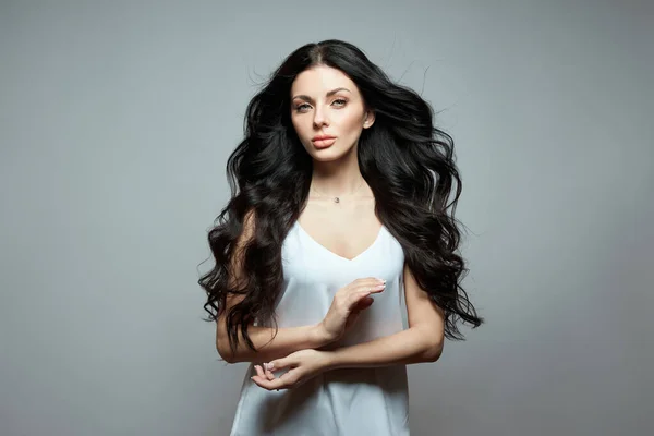 Uzun saçlı, kıvırcık saçlı, esmer bir kızın seksi moda kadını. Saç bakımı için doğal kozmetik ürünleri, güçlü kökler.