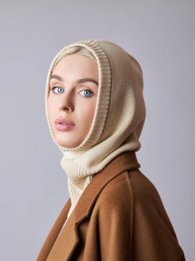 Kafasında başlık olan, sarı saçlı, Avrupalı Müslüman bir kadın. Yumuşak tenli güzel bir kız, doğal kozmetik ürünleri.